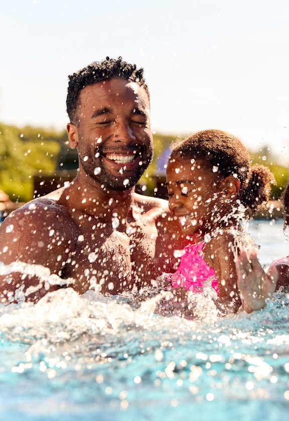 A family of four is enjoying a swim in a pool.