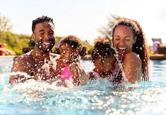 A family of four is enjoying a swim in a pool.