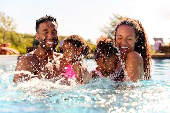 A family of four is enjoying a swim in a pool.