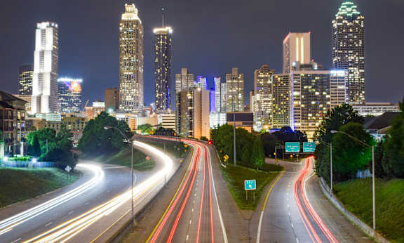A cityscape at night with a highway leading into the distance.