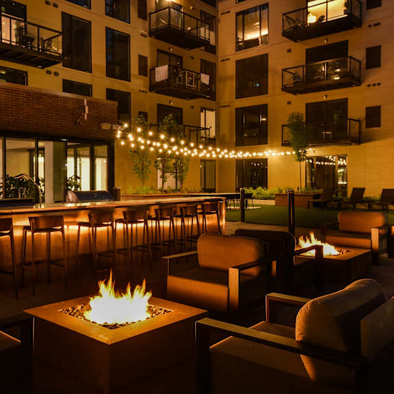 A patio with a fire pit and chairs.