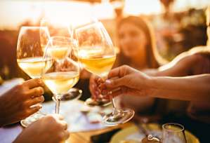A group of people toasting with glasses of white wine.