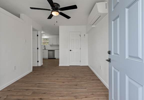 a renovated living room with white walls and a ceiling fan