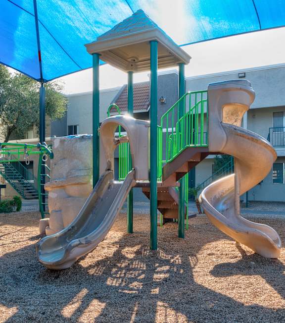 A playground with a slide and a green structure.