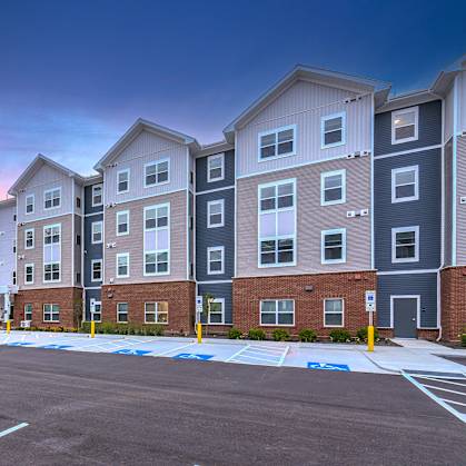 A parking lot in front of a row of apartment buildings.