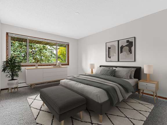 A bedroom with a large bed and a window overlooking a green tree.