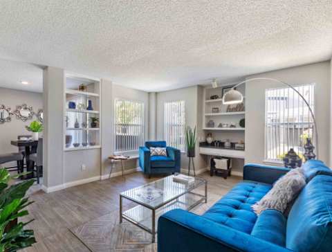 A living room with a blue couch and a glass coffee table.