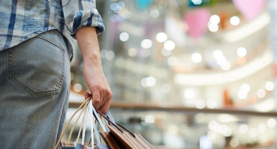 A person holding shopping bags in a mall.