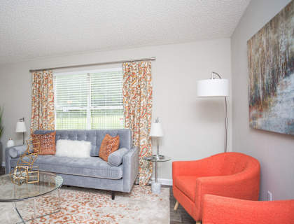 a living room with orange chairs and a couch and a window