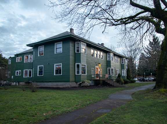 a green house with a sidewalk in front of it