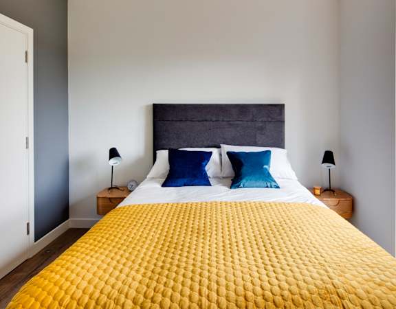 a bedroom with a yellow bedspread and blue pillows