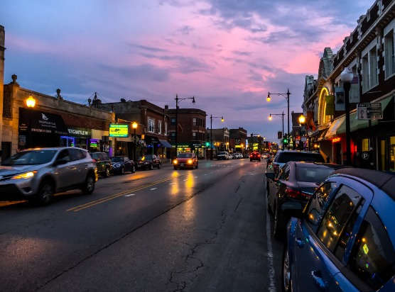 a city street at sunset with cars parked on the side of the road