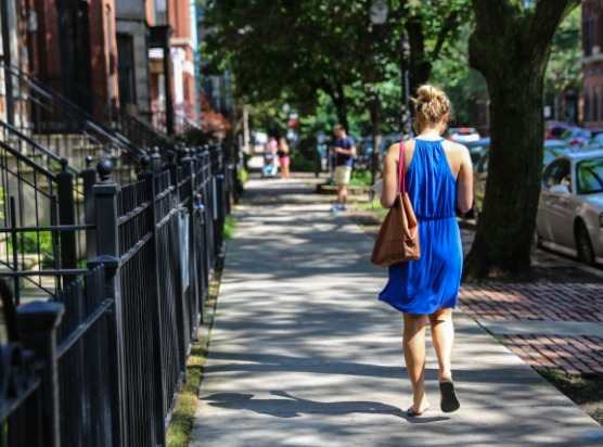 a woman in a blue dress walking down a sidewalk