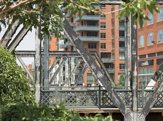 a metal bridge over a body of water with a building in the background