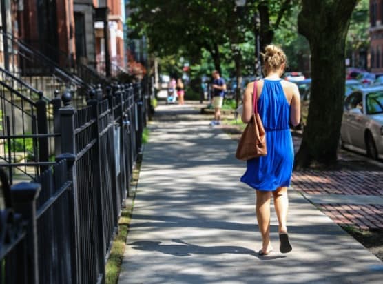 a woman in a blue dress walking down a sidewalk