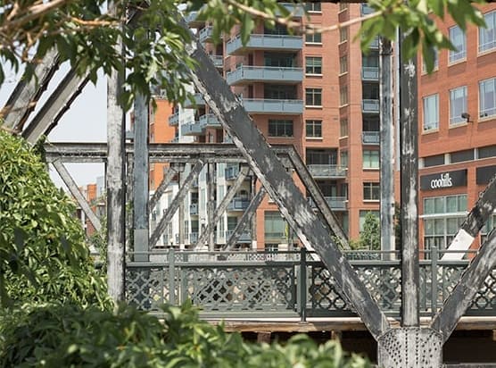 a metal bridge over a body of water with a building in the background