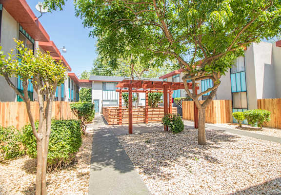 a courtyard with trees and a red wooden structure at Woodland Village Apartments , Woodland California