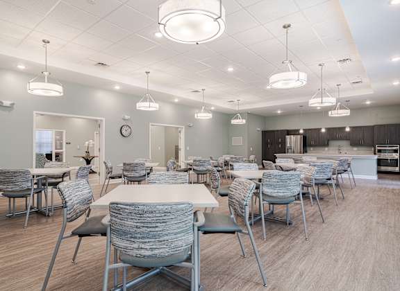 a large dining room with tables and chairs and a kitchen