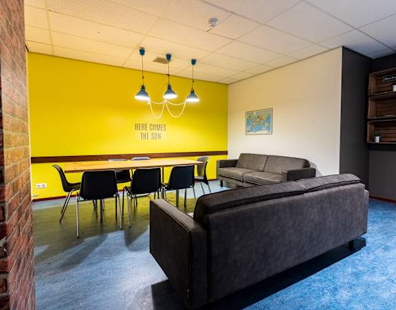 A room with a yellow wall and a sign that says "Here comes the sun".