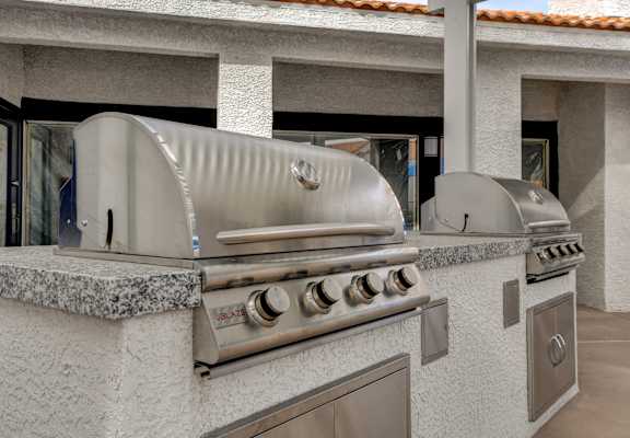 a stainless steel bbq grill is set up in the backyard of a home