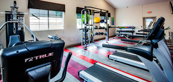 A gym with a variety of equipment including treadmills, weights, and exercise machines.