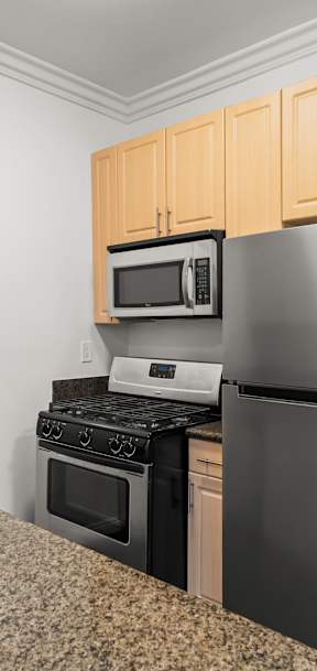 A kitchen with a stainless steel refrigerator, microwave, and oven.