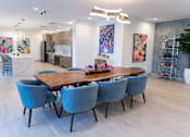 Thumbnail 2 of 6 - A dining room with a long table and blue chairs.