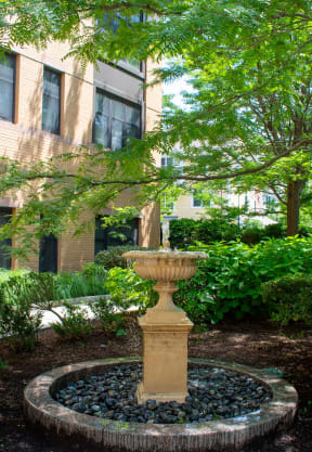 a fountain sits in the middle of a garden in front of a building