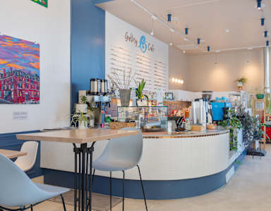 a cafe with a round table and chairs in front of a counter with coffee machines