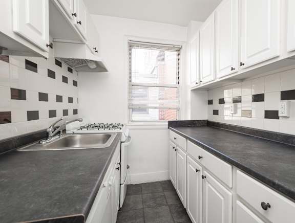 a kitchen with white cabinets and black countertops