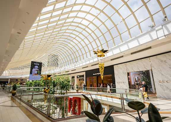 A shopping mall with a Gucci store and a large glass display.