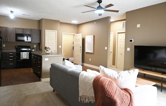 A living room with a grey couch and a ceiling fan.