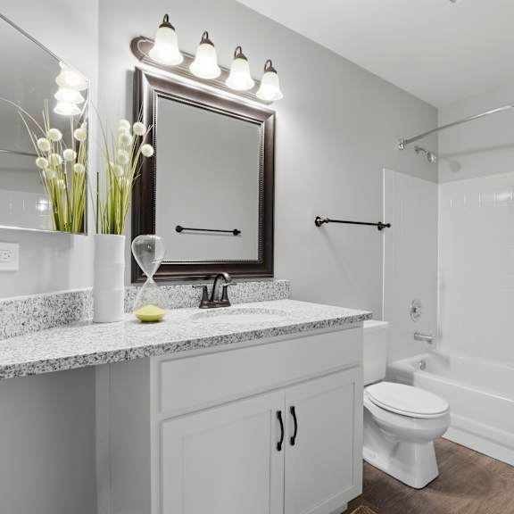 A white bathroom with a sink, toilet, and shower.