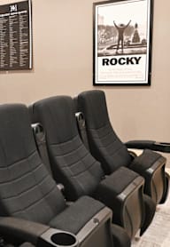 A home theater with a large screen and black chairs.