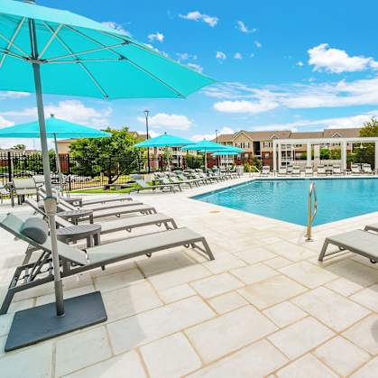 A poolside area with sun loungers and umbrellas. at The Vineyard of Olive Branch Apartment Homes, Olive Branch, MS