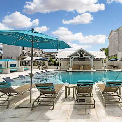 a swimming pool with chairs and umbrellas at the resort on a sunny day at Parkwest Apartment Homes, Hattiesburg, 39402