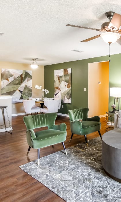 a living room with green walls and a white couch and green chairs at Crossgates Apartment Homes, Starkville