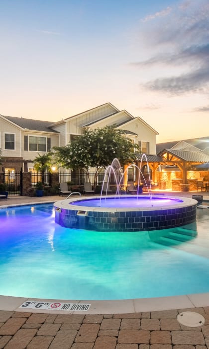 a swimming pool at night with houses in the background