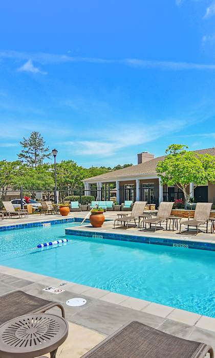A large swimming pool surrounded by lounge chairs and umbrellas.