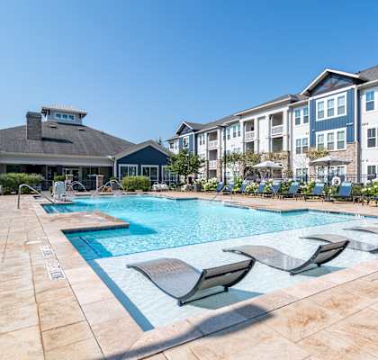 A swimming pool surrounded by lounge chairs and apartment buildings.