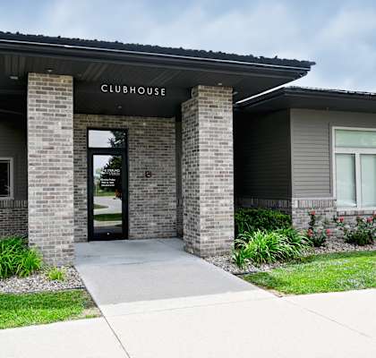 The front of a clubhouse with a glass door and windows.