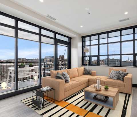 a living room with a couch and a coffee table and large windows