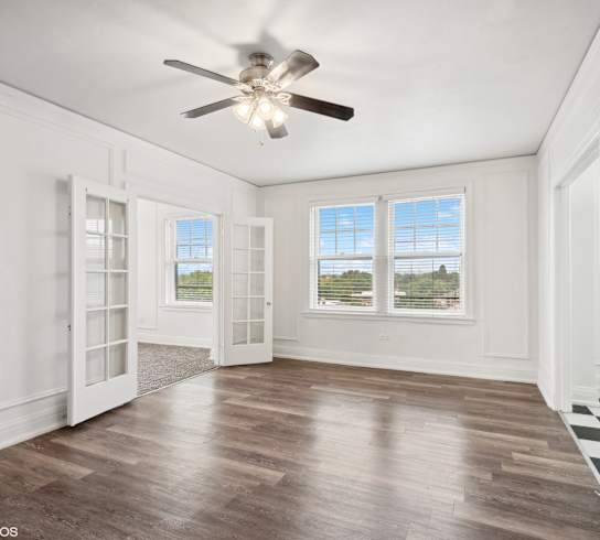 an empty living room with white walls and a ceiling fan at CWE Apartments, St. Louis, 63108