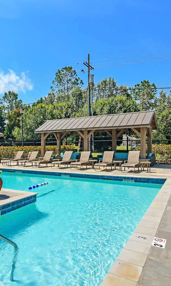 A pool with a slide and sun loungers.