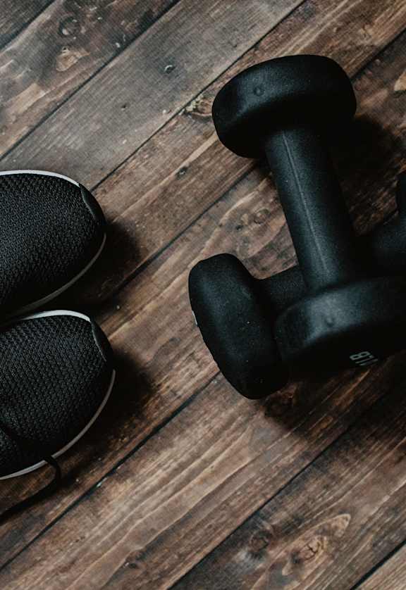 a pair of shoes and a dumbbell on a wooden floor