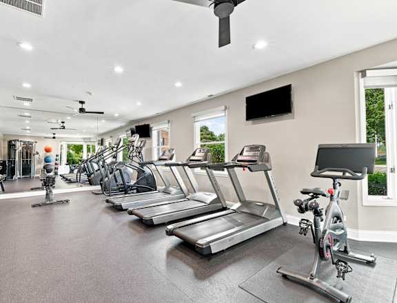 A spacious gym with treadmills, elliptical machines, and a stationary bike.