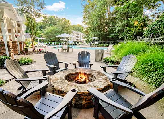 A fire pit surrounded by chairs in a backyard setting.