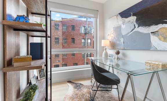 a home office with a glass desk and a large window