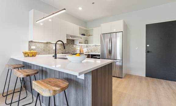 a kitchen with white cabinets and a large island with a sink and three stools
