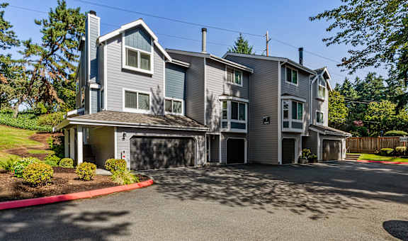 A large house with a grey and blue exterior and a driveway in front.